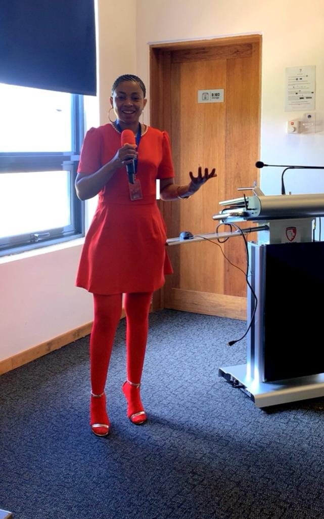 Mathato Aumane lecturing in a red dress with a microphone