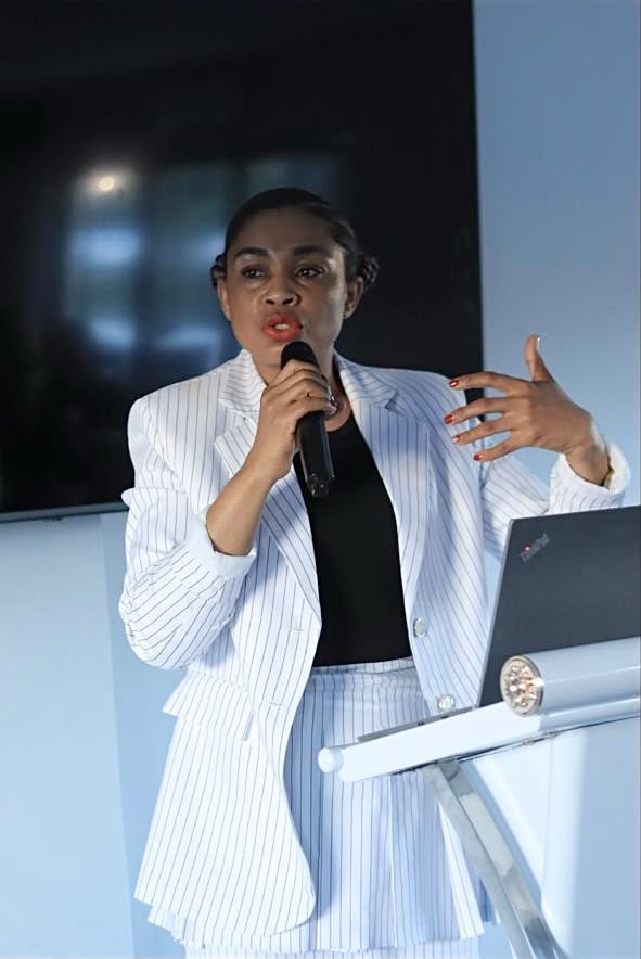 Mathato Aumane speaking with a microphone in a white pinstripe suit